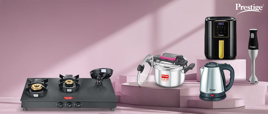Prestige kitchen appliances including black gas stove, silver pressure cooker, black air fryer, electric kettle, and hand blender on a pink background.