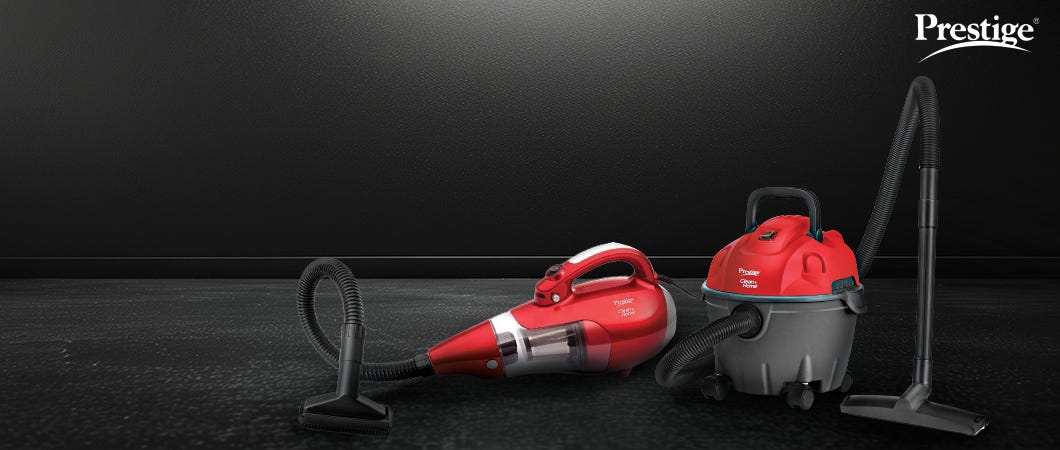 Two red Prestige vacuum cleaners, including a handheld and a wet-dry model, placed on a black surface for efficient home cleaning.